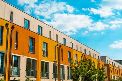 Rangée de bâtiments modernes avec façades orange et neutres, probablement des bureaux ou coworking.