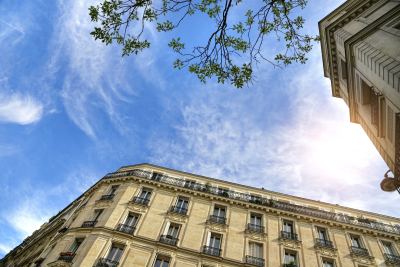 Façade typique d'un immeuble parisien haussmannien avec balcons en fer forgé et grandes fenêtres.