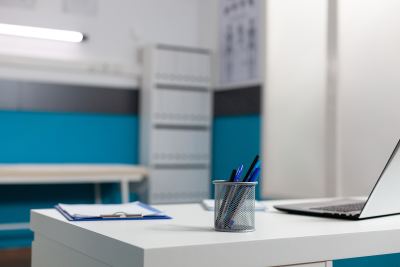 Bureau blanc minimaliste avec ordinateur, pot à crayons et bloc-notes dans un espace de coworking
