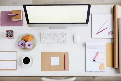 Bureau moderne et épuré avec ordinateur, carnets et tasse de café dans un espace de coworking