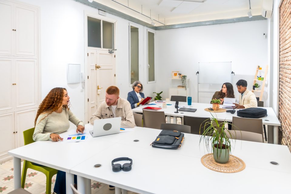 Espace de coworking lumineux avec bureaux partagés, ordinateurs et plantes d'intérieur