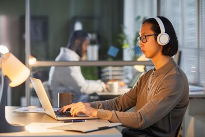 Personne concentrée avec casque audio dans un espace de coworking lumineux et contemporain