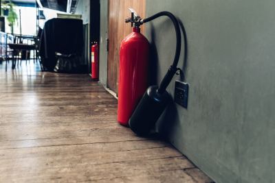 Extincteur rouge avec tuyau noir fixé au mur dans un couloir d'un espace de coworking