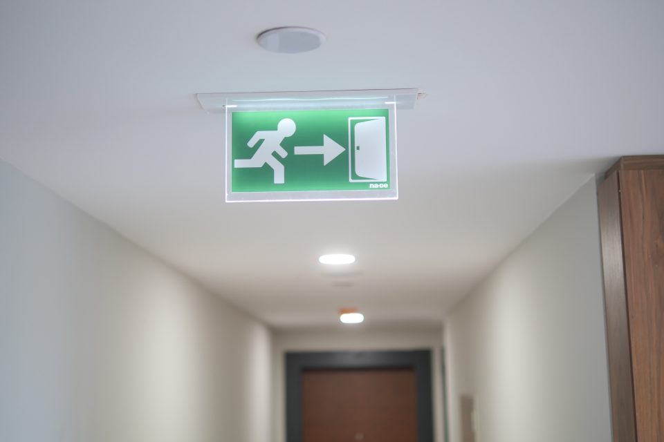 Panneau lumineux de sortie de secours vert installé au plafond d'un couloir professionnel
