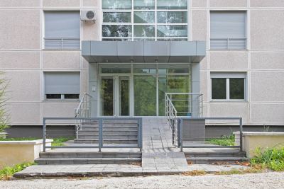 Entrée d'un immeuble de bureaux moderne avec porte vitrée et rampes d'accès pour PMR
