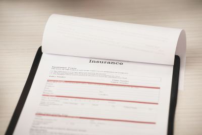 Formulaire d'assurance posé sur une surface en bois clair, partiellement rempli.