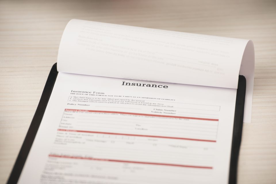 Formulaire d'assurance posé sur une surface en bois clair, partiellement rempli.