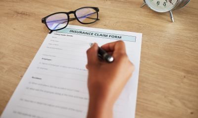 Formulaire de réclamation d'assurance posé sur un bureau en bois avec lunettes et montre