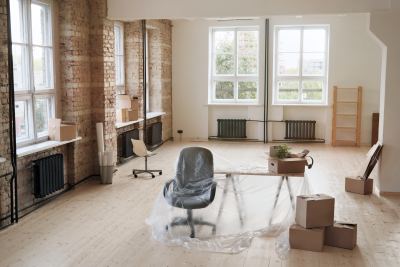 Grande pièce lumineuse avec murs en briques et parquet clair, meubles de bureau en cours d'installation.