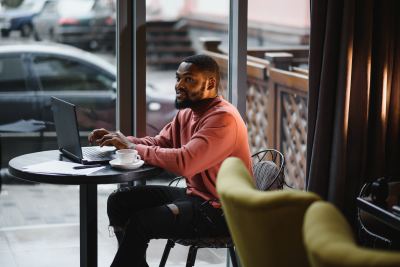 Un homme utilise un ordinateur portable dans un espace de coworking lumineux avec une tasse de café.