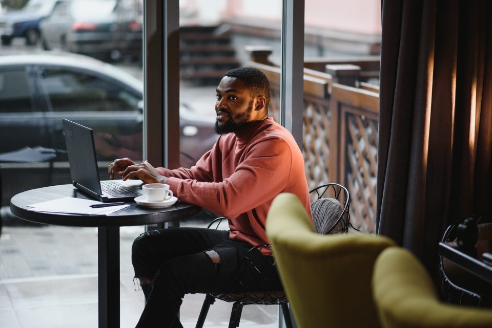 Un homme utilise un ordinateur portable dans un espace de coworking lumineux avec une tasse de café.