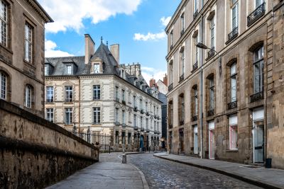Rue pavée typique d'un centre-ville historique à Rennes avec bâtiments en pierre et toits en ardoise.