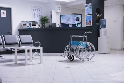 Espace de réception avec chaises, fauteuil roulant et comptoir d'accueil dans un coworking médical