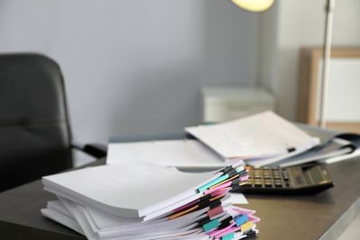 Bureau de travail chargé avec documents, stylos, calculateur et fauteuil ergonomique