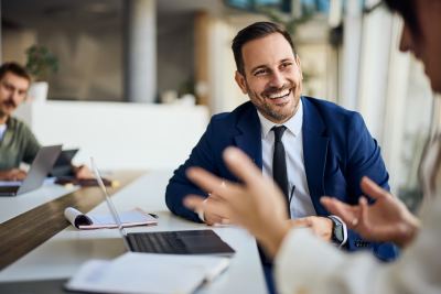 Professionnel en costume bleu discutant avec un collègue dans un espace de coworking moderne.
