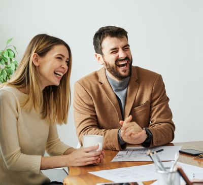 Deux professionnels discutent dans un bureau moderne et convivial, entourés de documents.