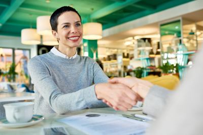 Deux personnes se serrent la main dans un espace de coworking moderne et chaleureux