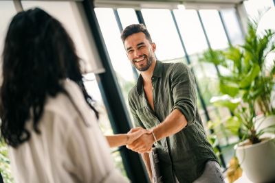 Un homme et une femme se serrent la main dans un espace de coworking lumineux et moderne.