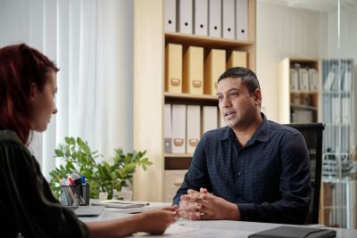Deux personnes en réunion dans un bureau moderne avec étagères organisées et plantes vertes