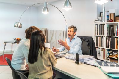 Réunion professionnelle dans un espace de coworking moderne avec des lampes suspendues et des étagères organisées.